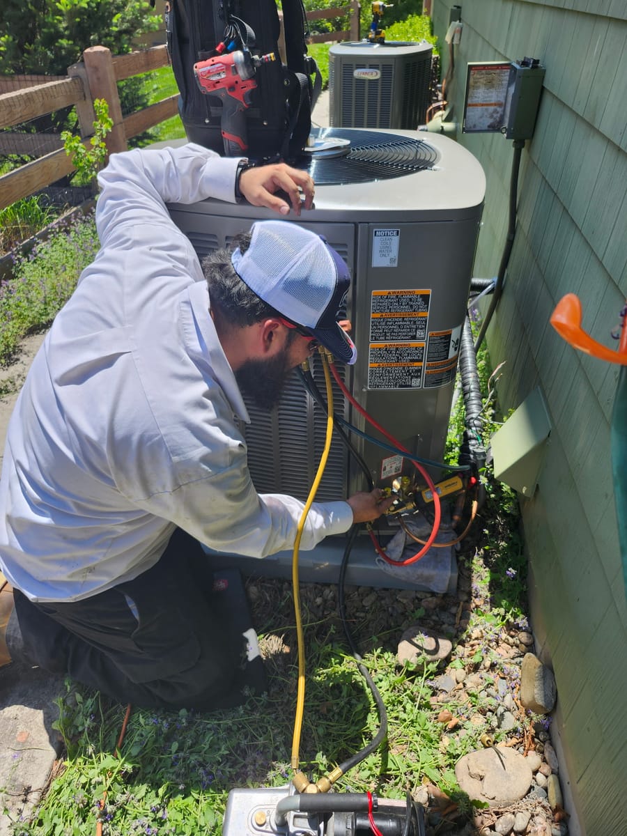 tech servicing an hvac unit outside of a home