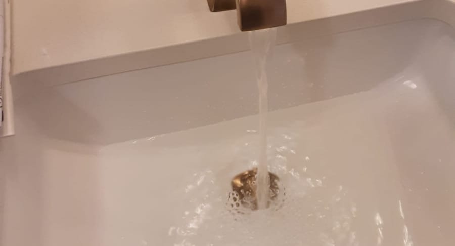 Water rushing out of faucet into stopped drain.