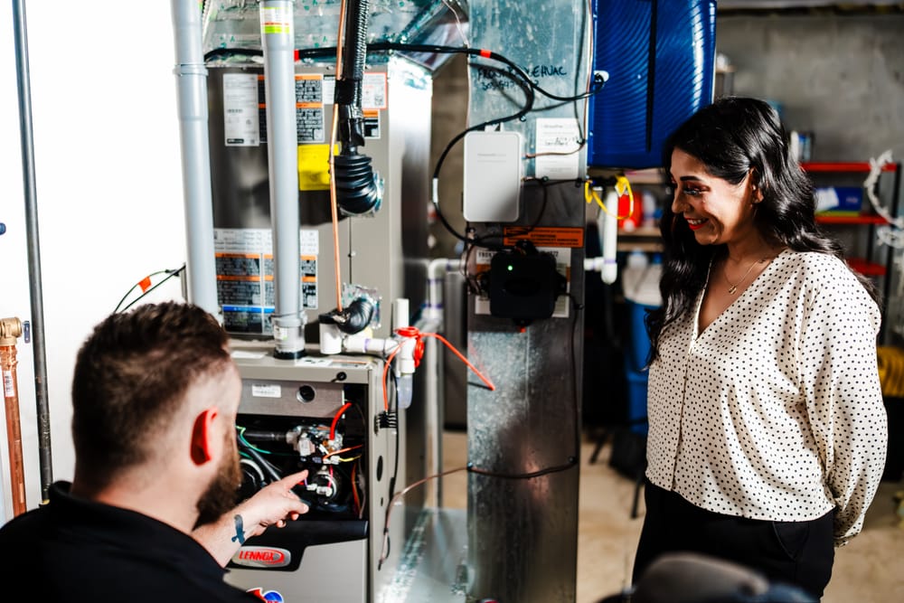 Heart technician showing client open furnace repairs.