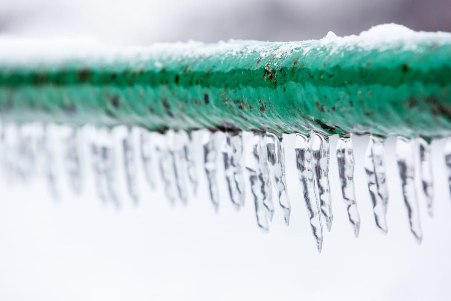 a frozen burst pipe with icicles hanging off it.
