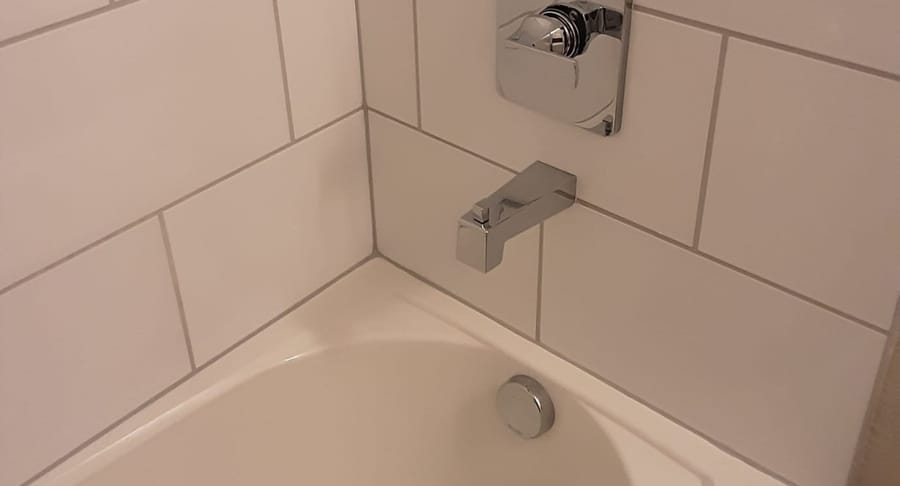 Tub spout on white tiles.