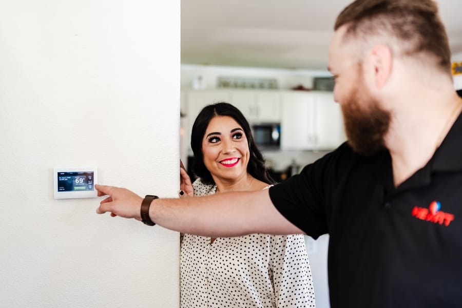 tech with customer and smart thermostat on wall