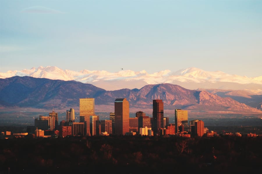 Skyline view of Denver, Colorado with buildings and mountains in the background