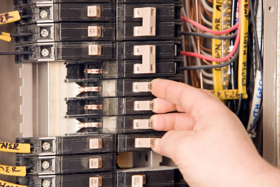 Electrician flipping the switches on an electrical panel as it is inspected